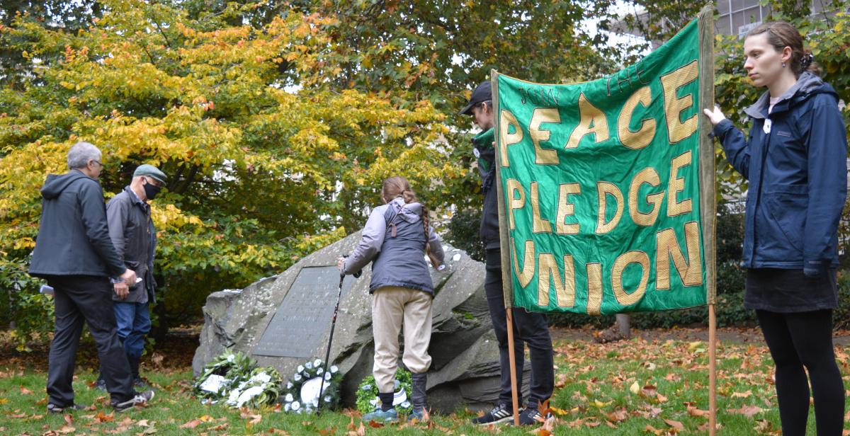 People place white poppy wreaths in Tavistock Square, London, with a Peace Pledge Union banner nearby