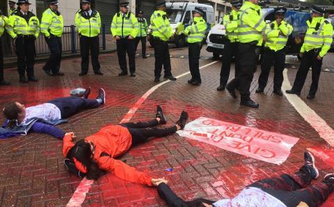 People lying in the road to the DSEI arms fair, surrounded by police