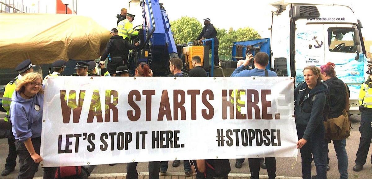 Protest at DSEI with a banner reading "War starts here"