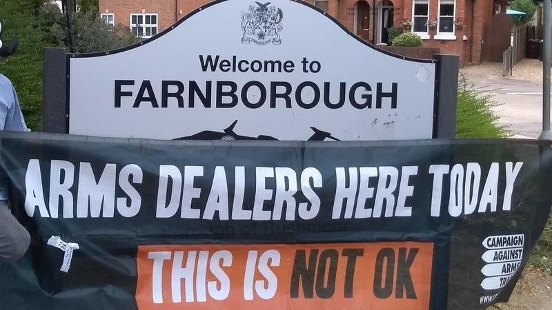 Anti-arms trade banner next to sign for Farnborough